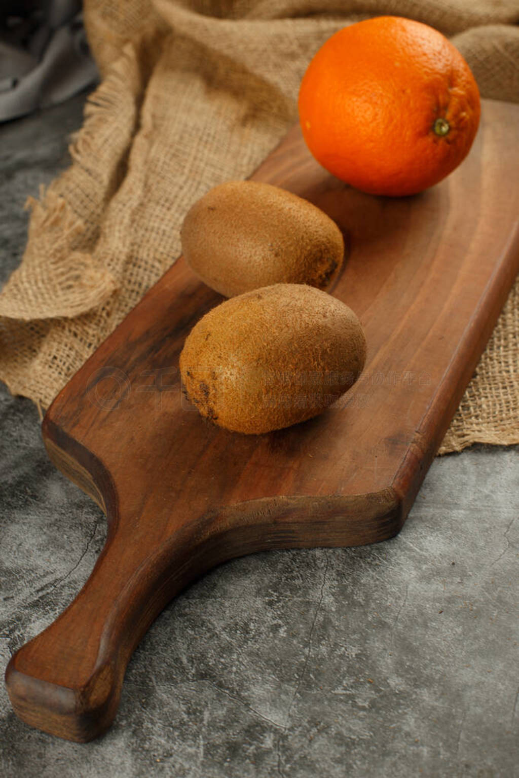 Orange and kiwies on a cutting board.