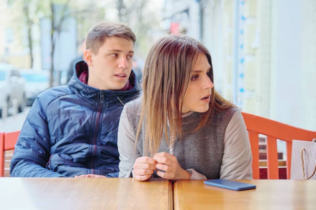 Emotional surprised young couple in outdoor cafe, sitting at the