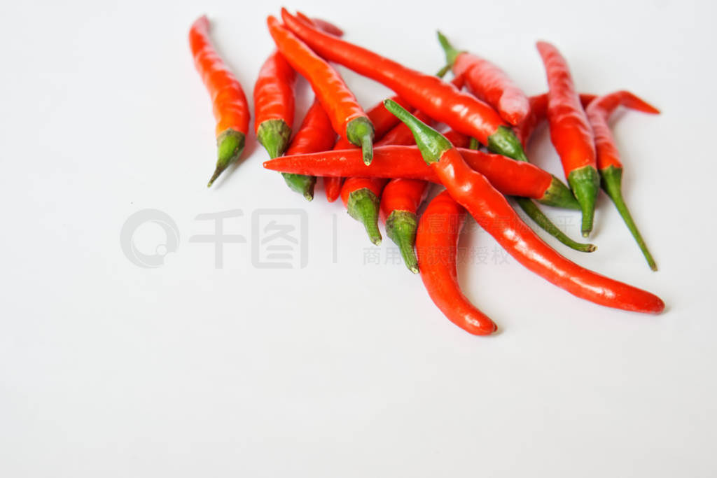 Pods of red hot chili pepper lie on a white surface. Free space