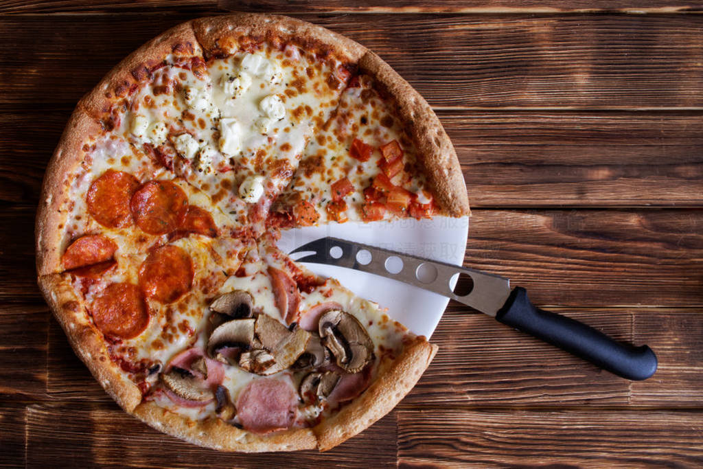 Composite pizza-assorted and cheese knife lie on a natural woode