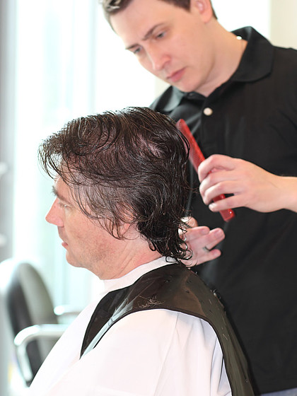 一个人在一家理发店理发大师年轻设计师专注于灰色的头发