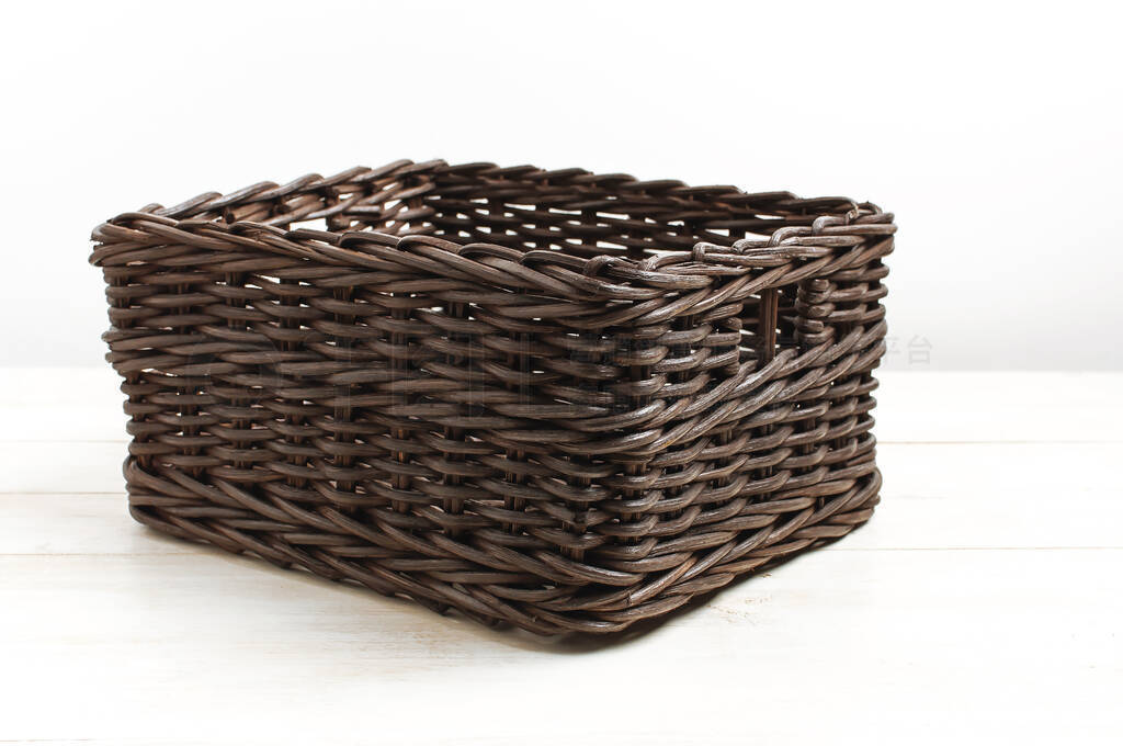 Empty wicker brown rattan basket on a white wooden background an