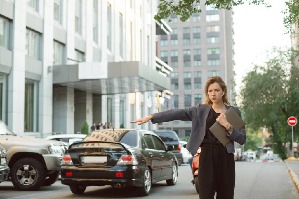 Busy successful businesswoman in formal wear catching a taxi on