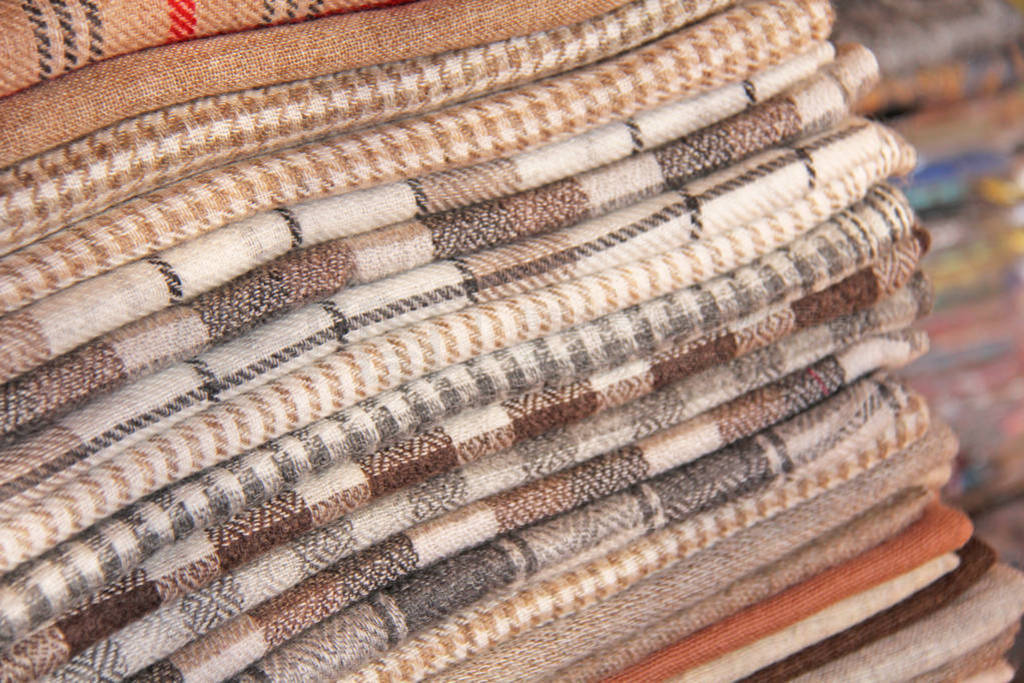 A stack of stoles of cashmere wool is brown and beige in a cage
