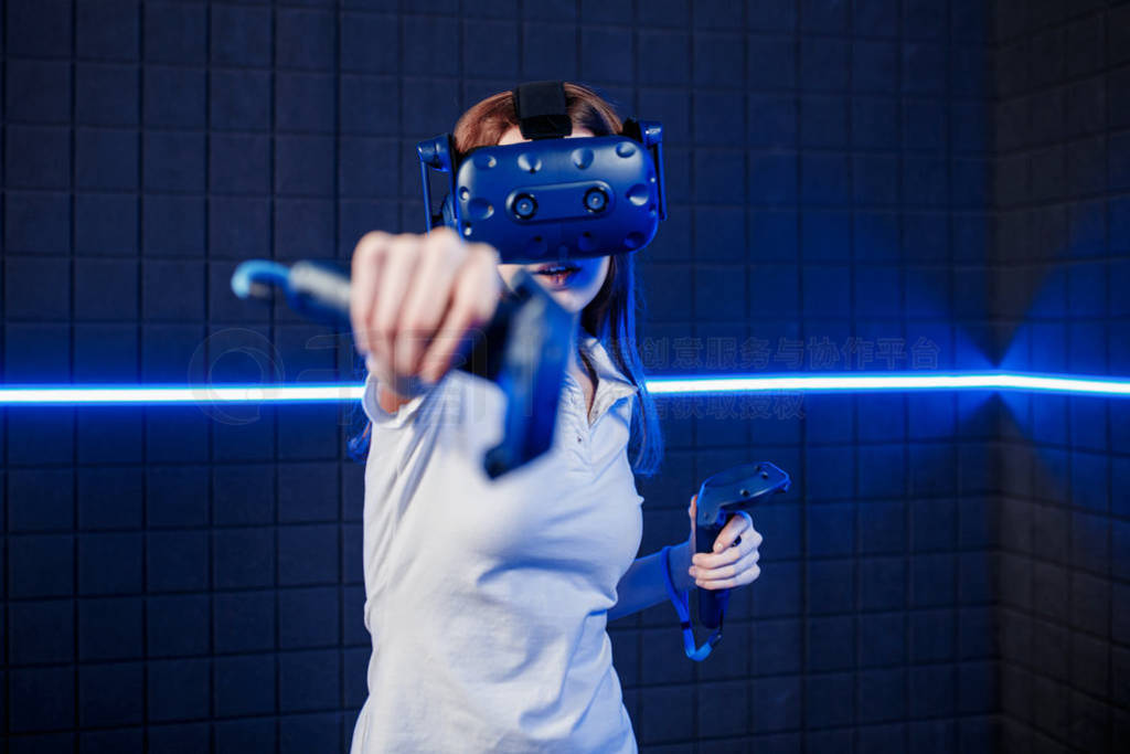 A young girl in a virtual reality helmet in the game room is pla