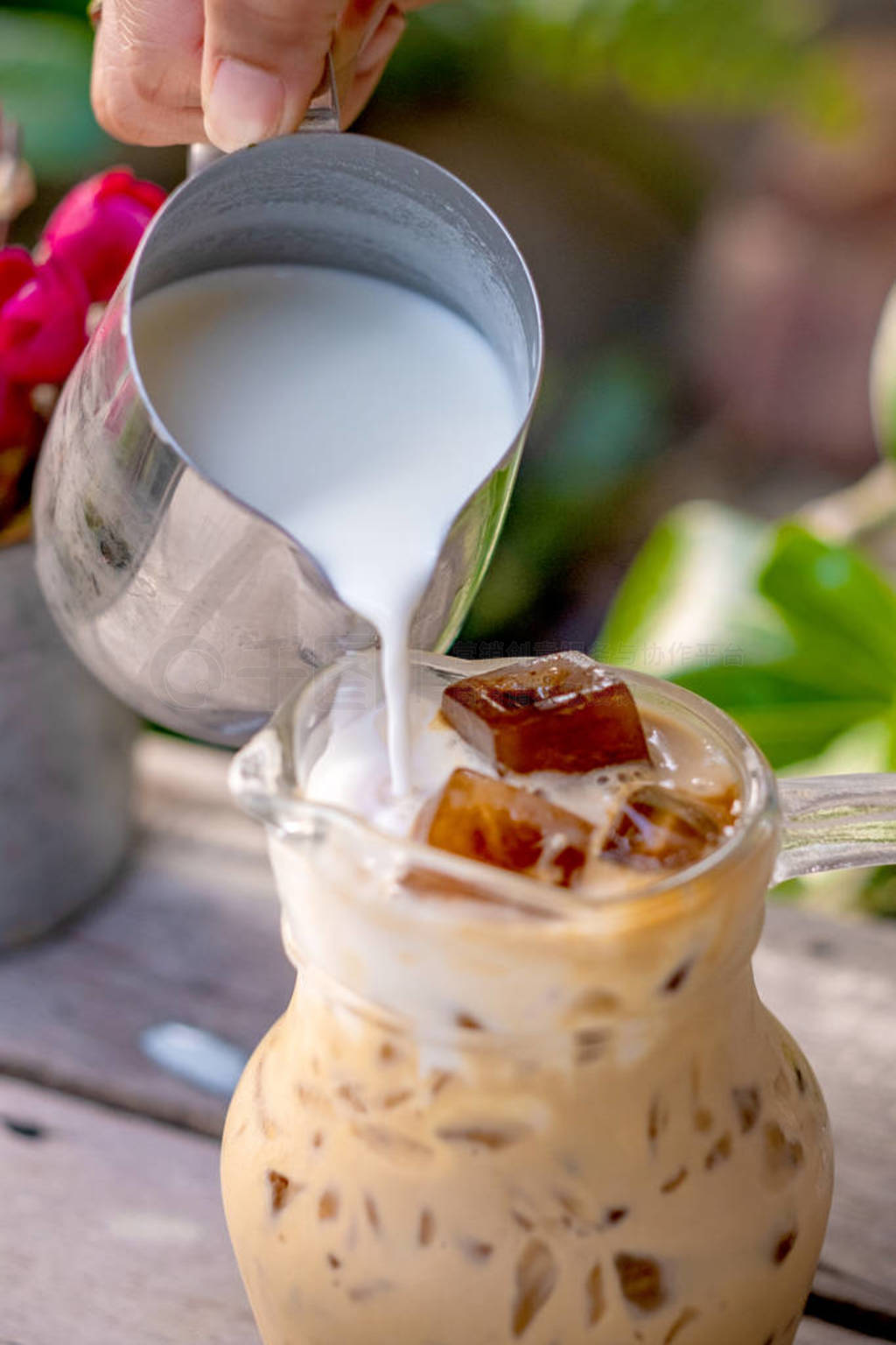 Pouring milk in a glass with latte coffee and iced