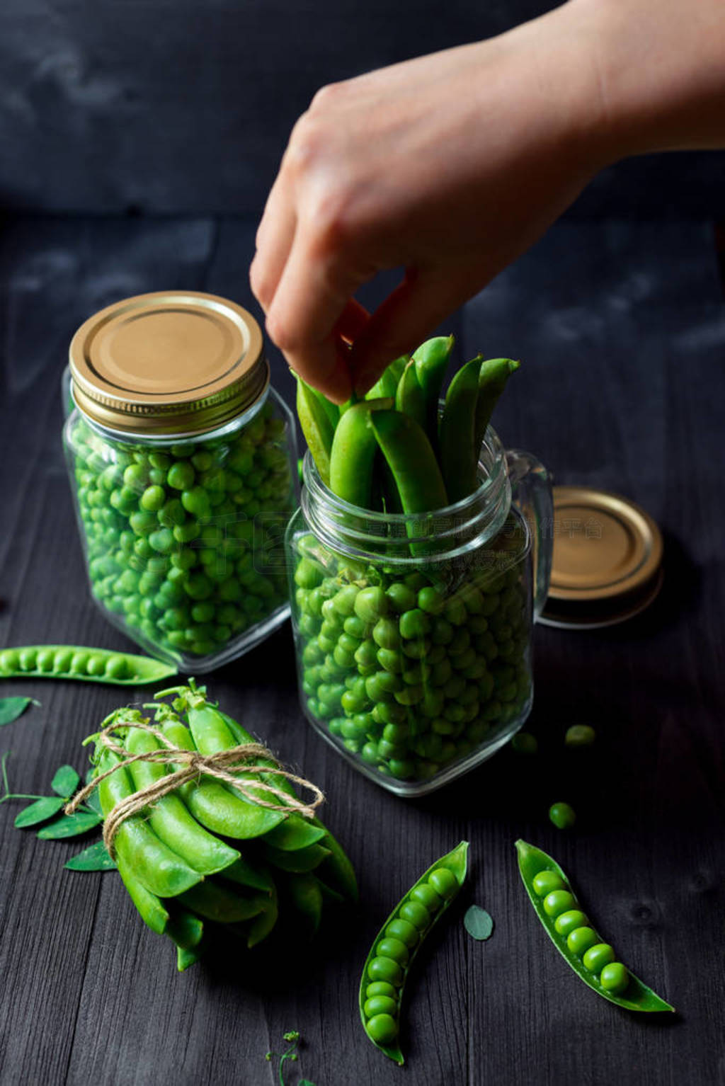 s hand taking green pea pod from jar