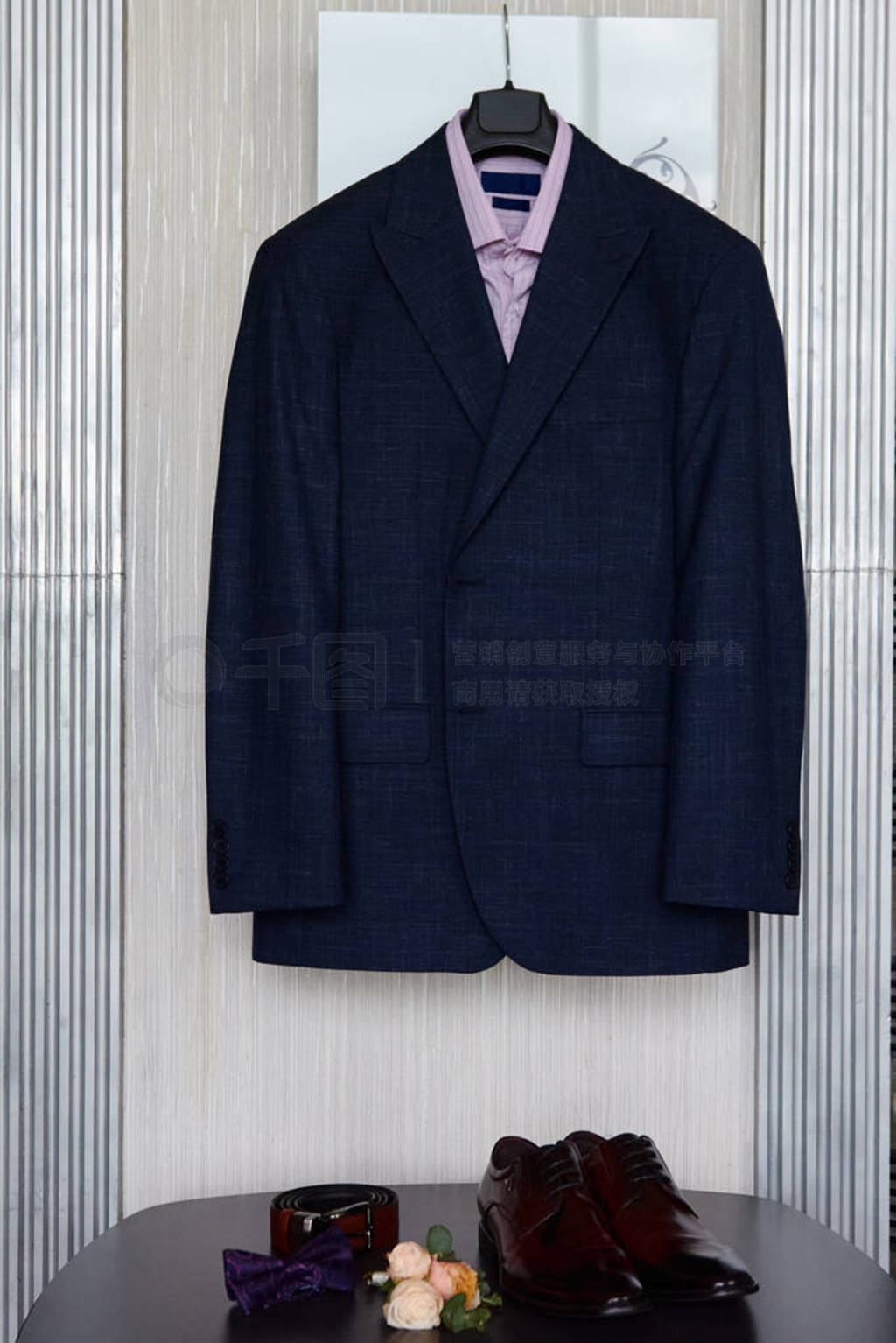 Elegant male suit with purple shirt hanging on wall and bow tie,