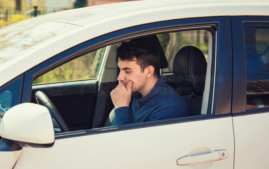 Thoughtful young man driver holding his hand under chin looking