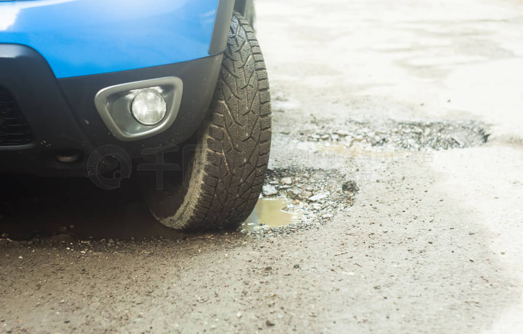 car tire in damaged road with hole in the asphalt. focus on the