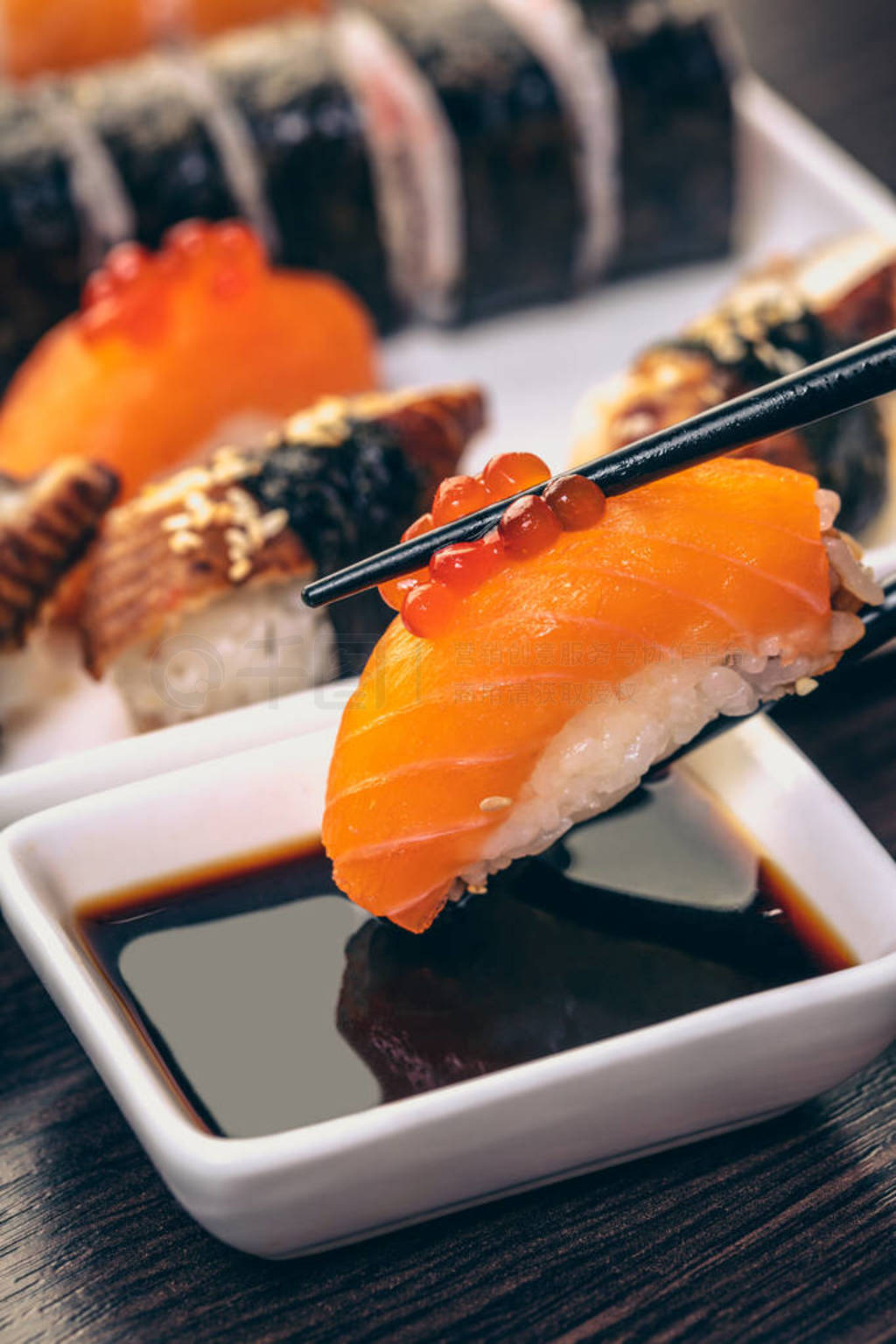sushi with salmon dipped in soy sauce