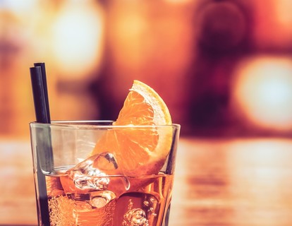 玻璃喷点发胶开胃酒 aperol 鸡尾酒与橙片和冰块上的酒吧桌，复古大气背景的细节