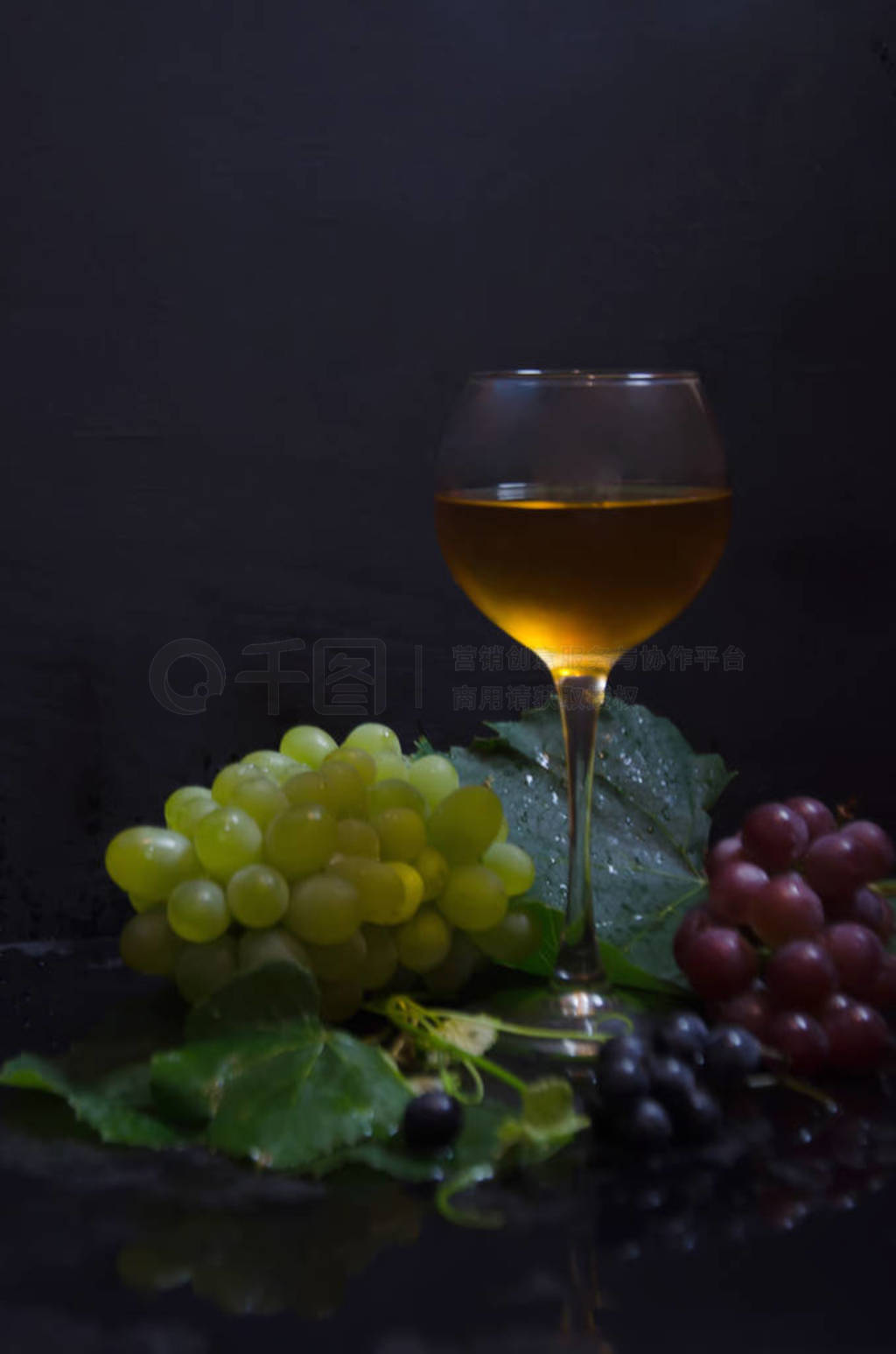 grape brush and leaves and wine glass on black background