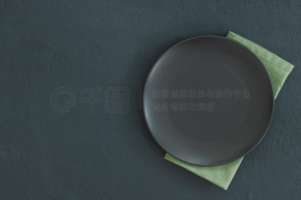 Empty black plate on dark stone background.