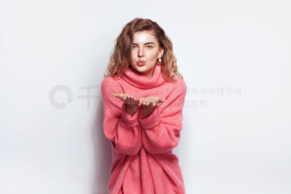BEautigul woman in pink sweater blowing a kiss