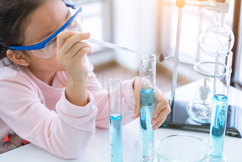 Asian child chemist holding flask and test tube in hands in lab