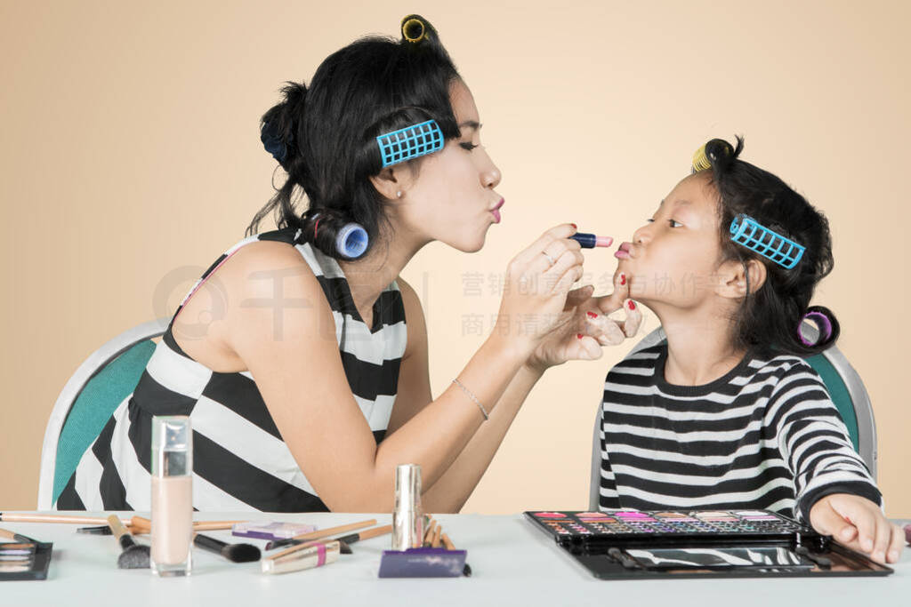 Young woman applies a lipstick to lips of her child