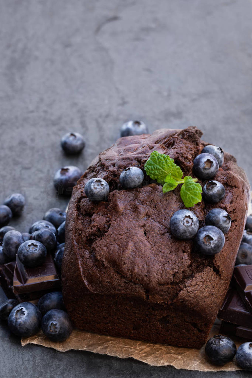 Homemade chocolate loaf cake with blueberry on black stone backg