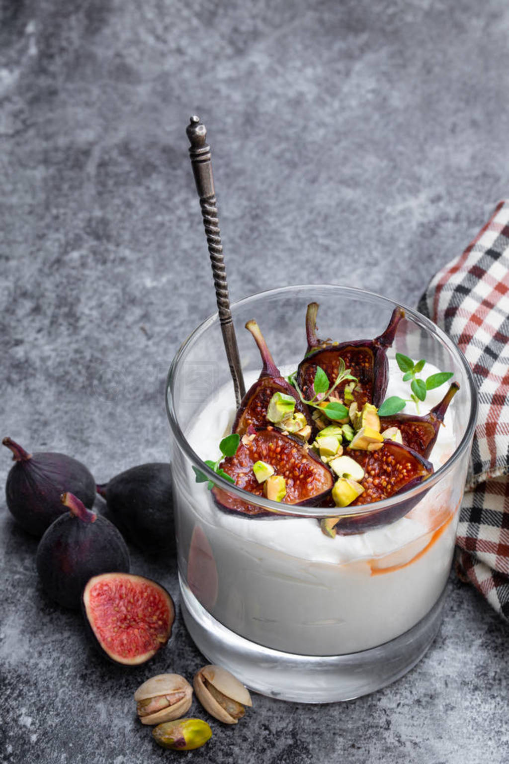 Homemade yogurt with grilled figs and pistachio on gray table