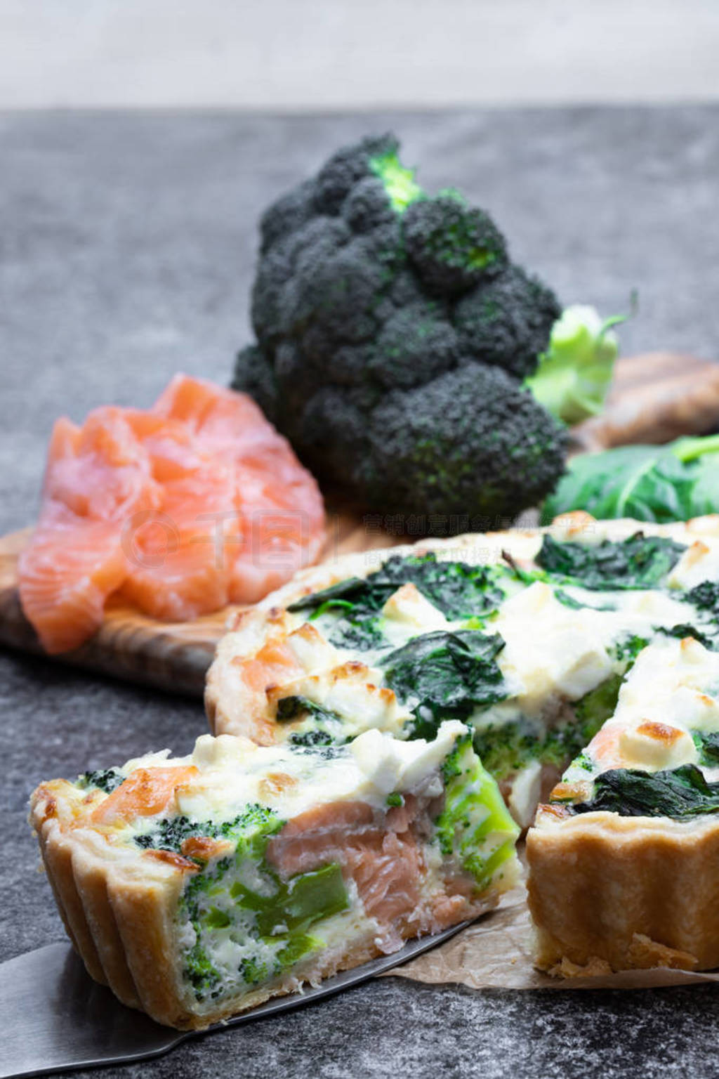 Raw salmon quiche wich broccoli and spinach on gray table