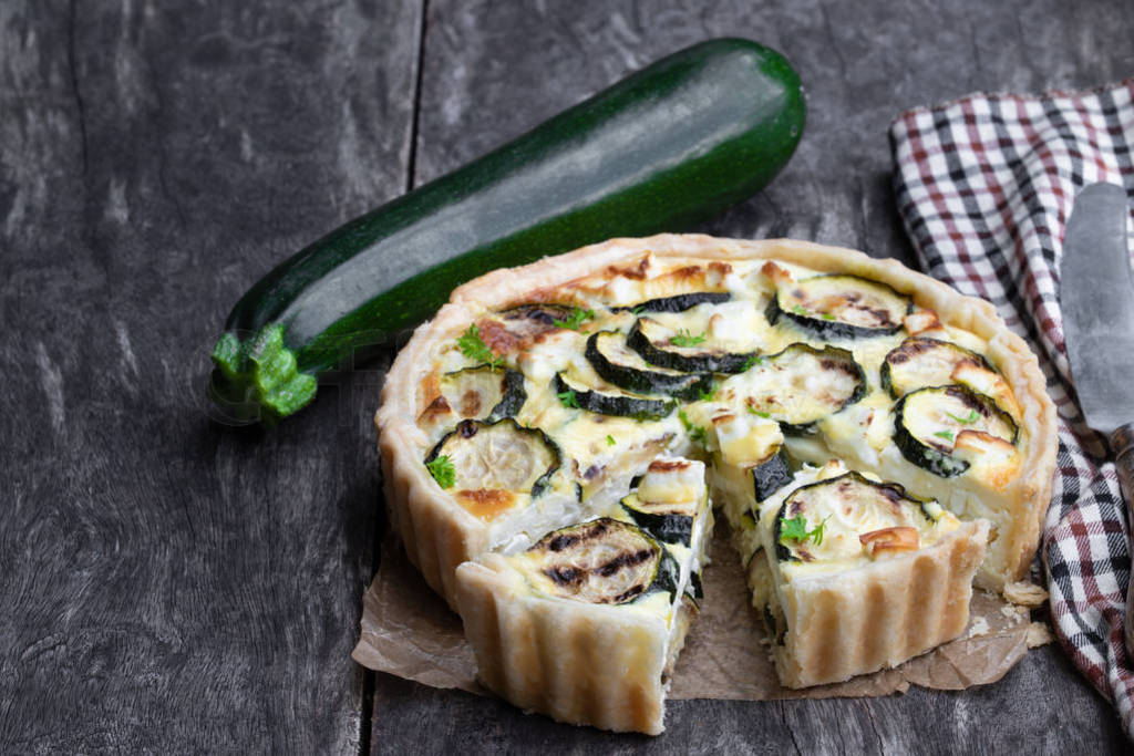 Homemade courgette and feta quiche on white wooden table