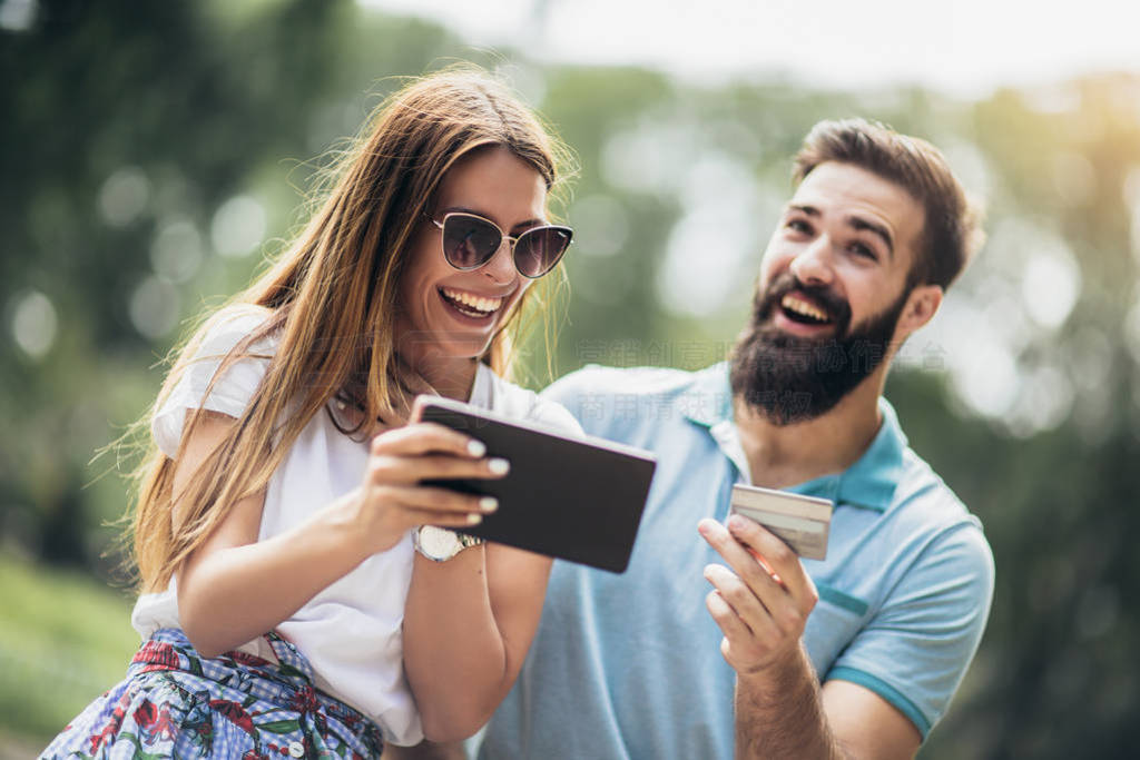 Happy couple paying on line with credit card and digital tablet