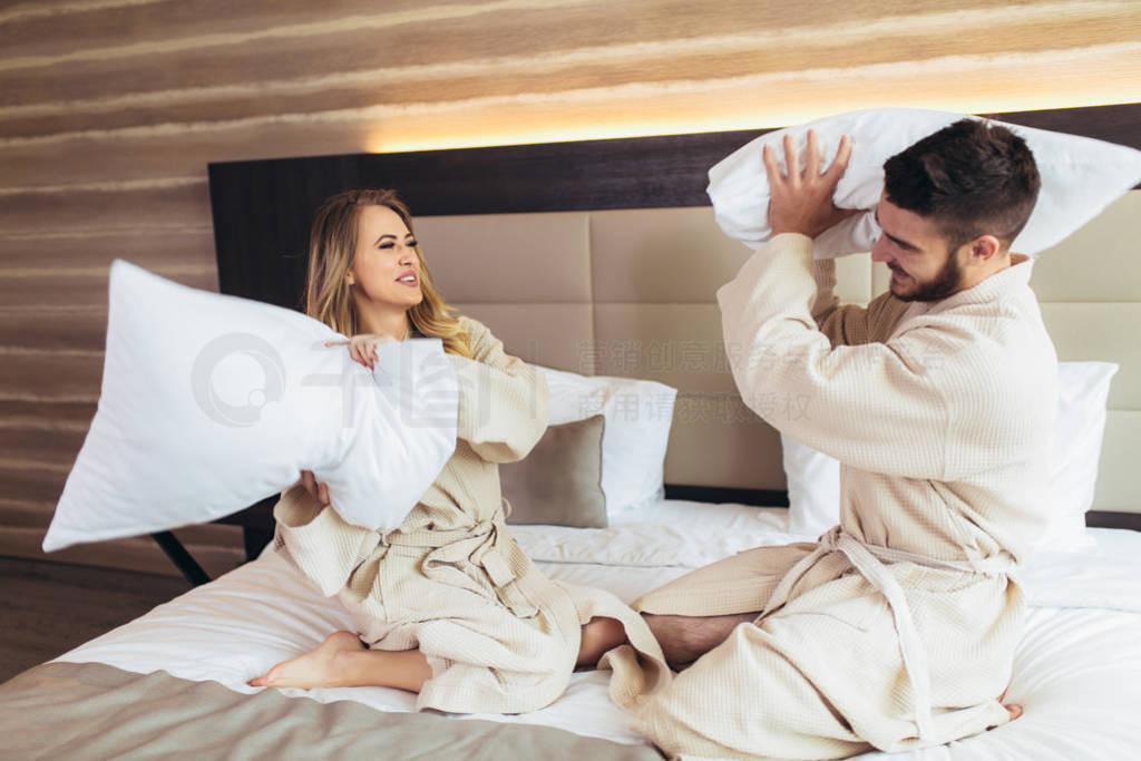 Happy Couple Having Pillow Fight in Hotel Room