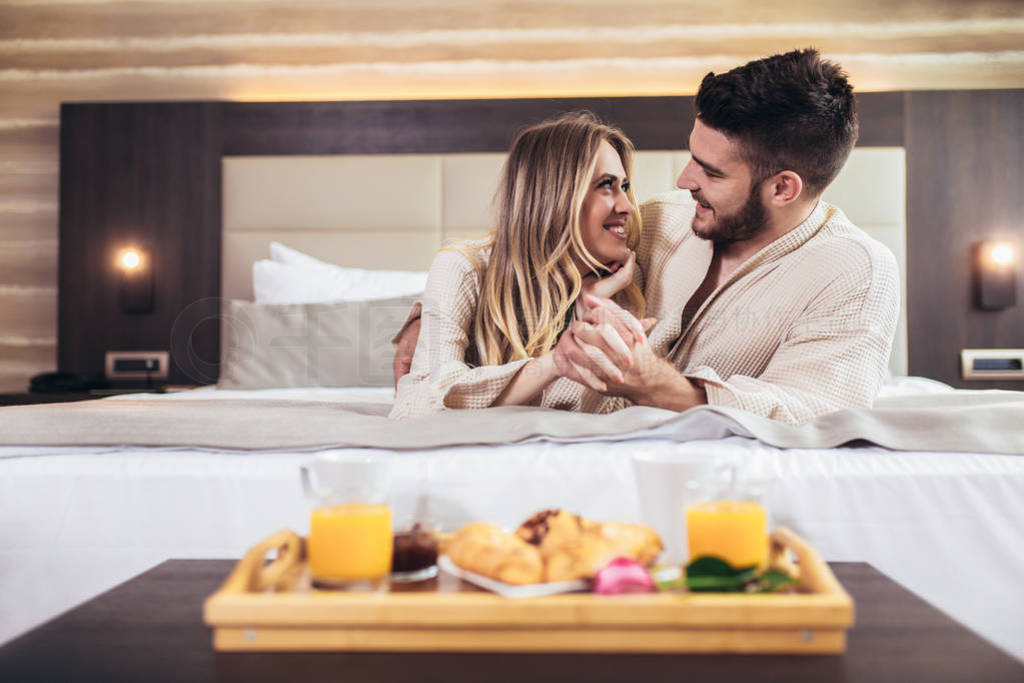 Young happy couple having breakfast in luxury hotel room.