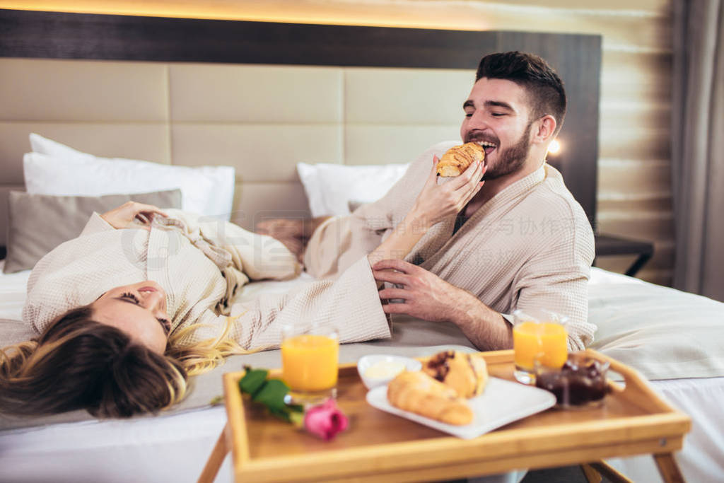 Young happy couple having breakfast in luxury hotel room.