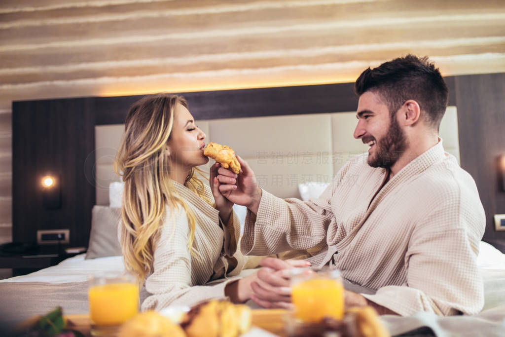 Young happy couple having breakfast in luxury hotel room.