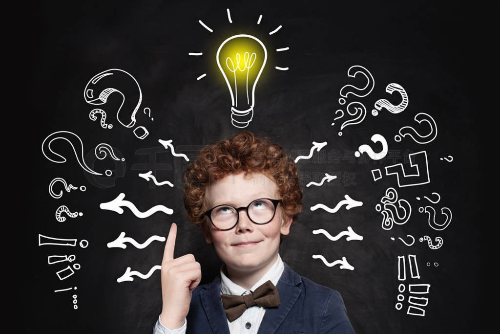 Cute boy student pointing up and looking at lightbulb