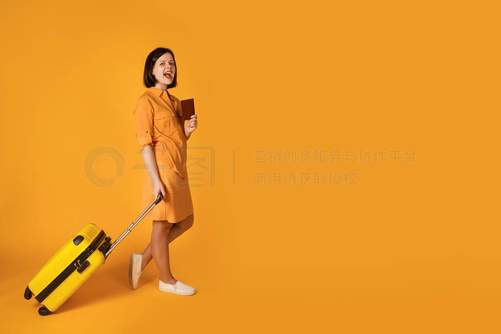 Pretty woman with suitcase on bright yellow background.