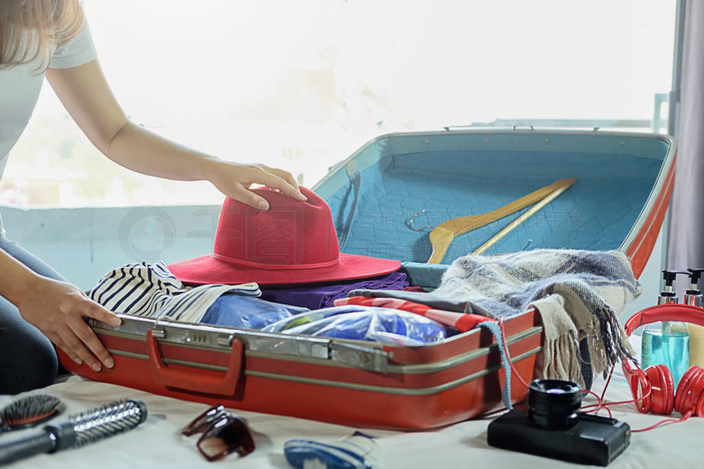 People packed suitcase with travel accessories on bed. Vacation