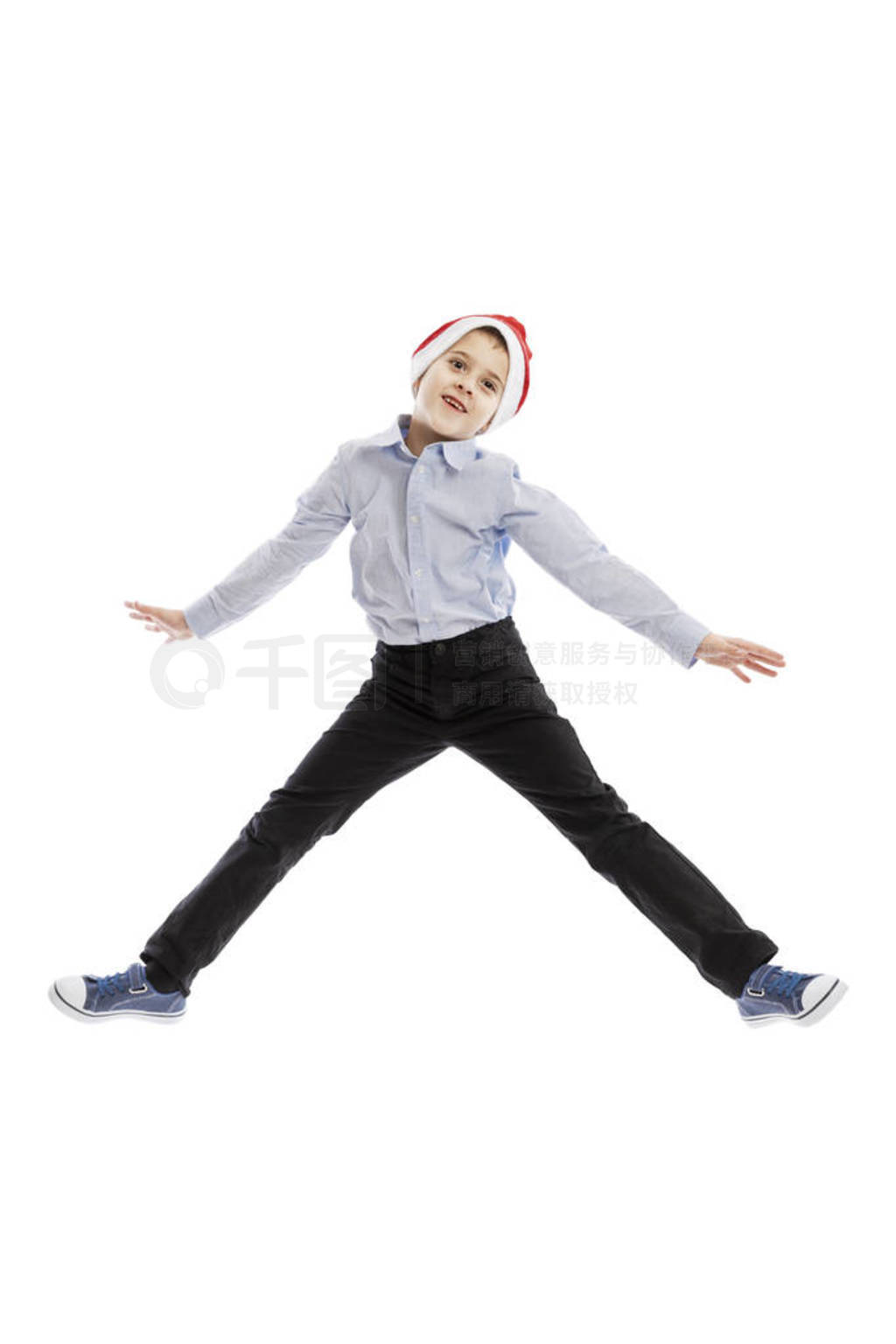 Smiling jumping schoolboy in Santa's hat. Full height. Christmas