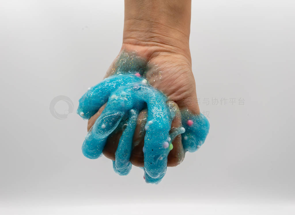 Hand playing transparent blue glitter slime isolated on white