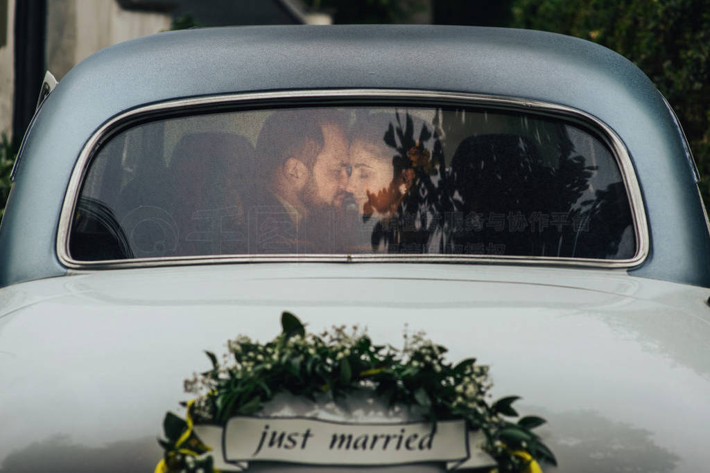 Happy luxury wedding couple kissing and embracing near retro car