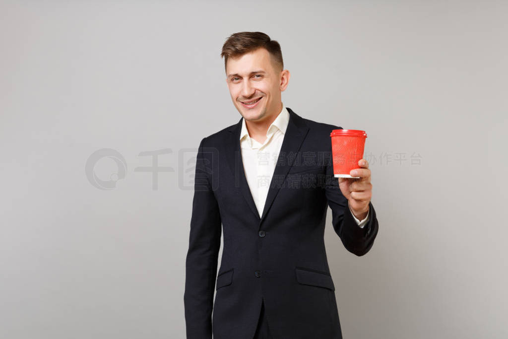 Smiling young business man in classic black suit, shirt holding