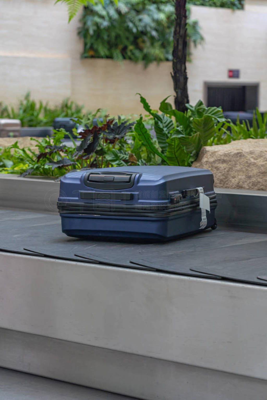 Blue suitcase on conveyor belt at arrival terminal in airport