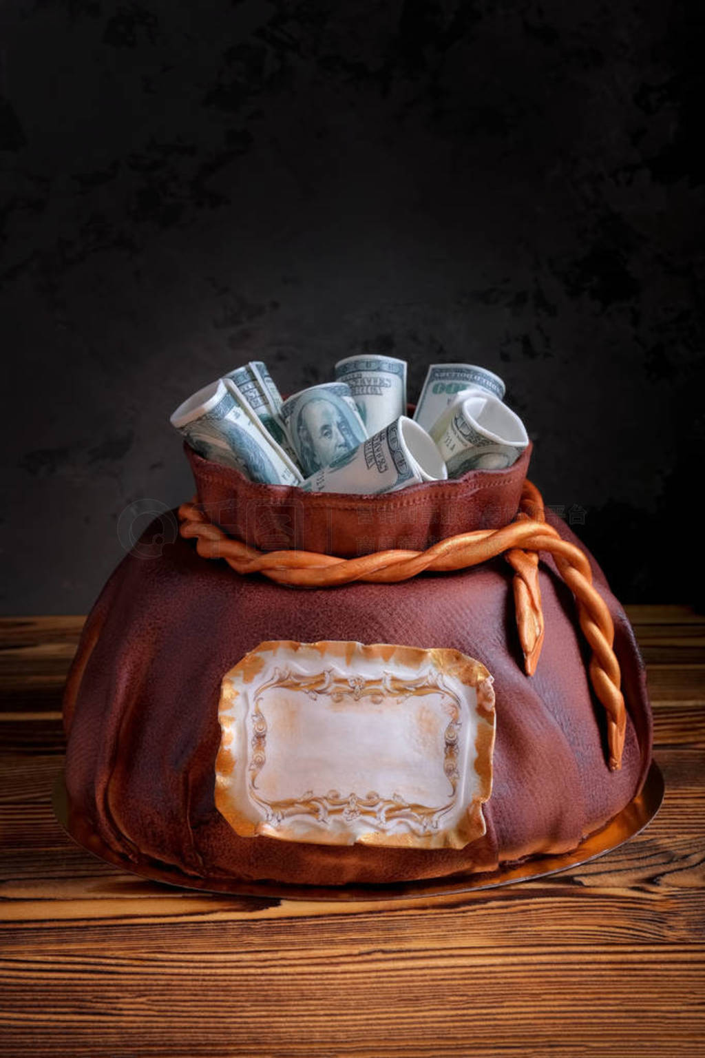 cake in shape of money bag with cash on top on wooden table.