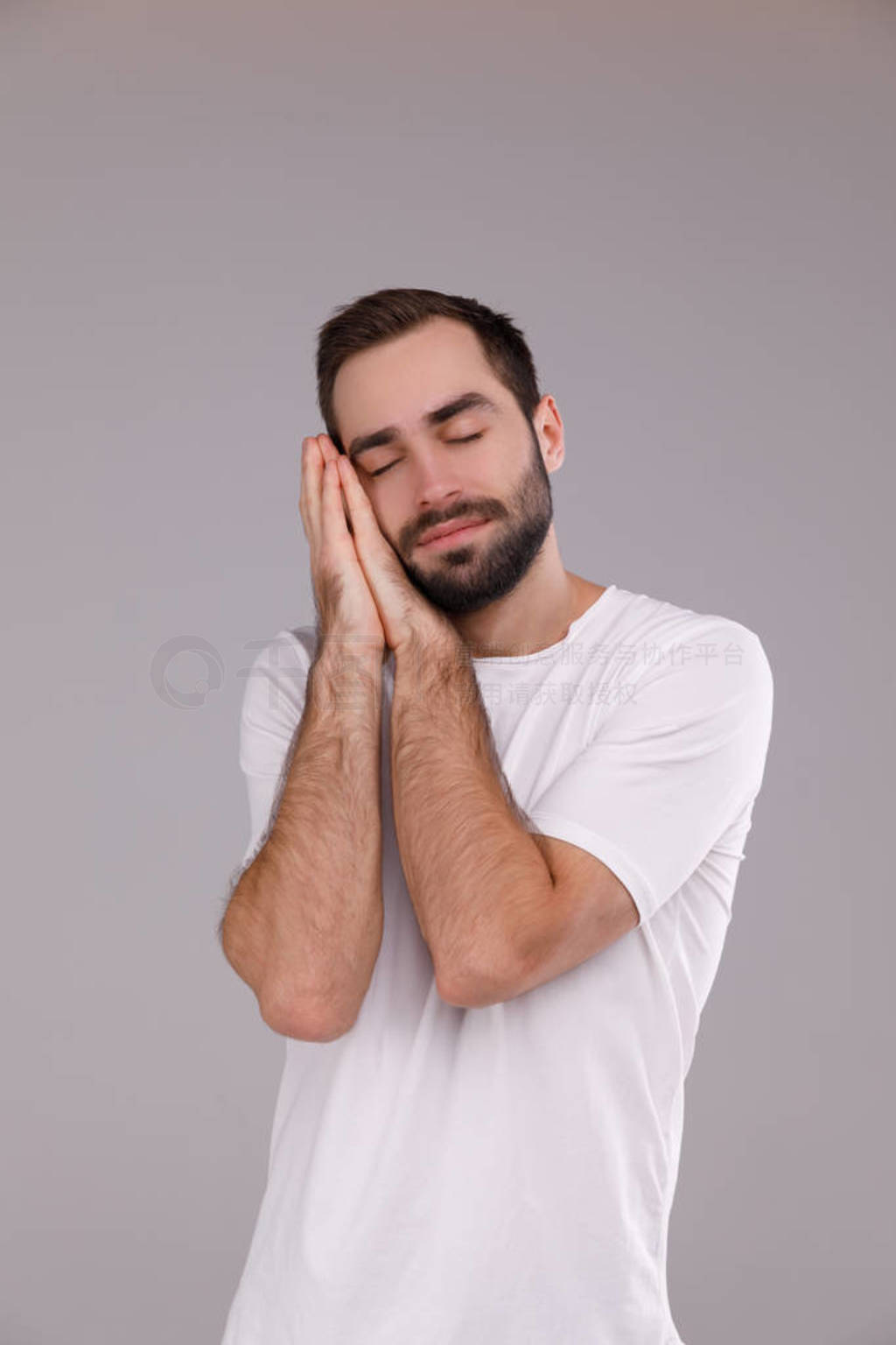 man with a beard in a white T-shirt on a grey background