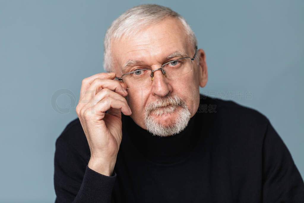 Old pensive handsome man with gray hair and beard in eyeglasses
