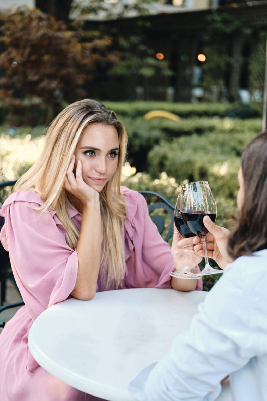 Young beautiful blond woman with glass of wine dreamily looking