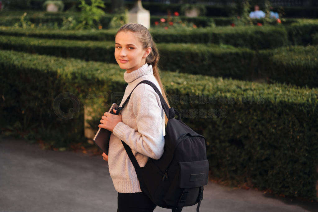 Attractive smiling student girl in cozy sweater with laptop and