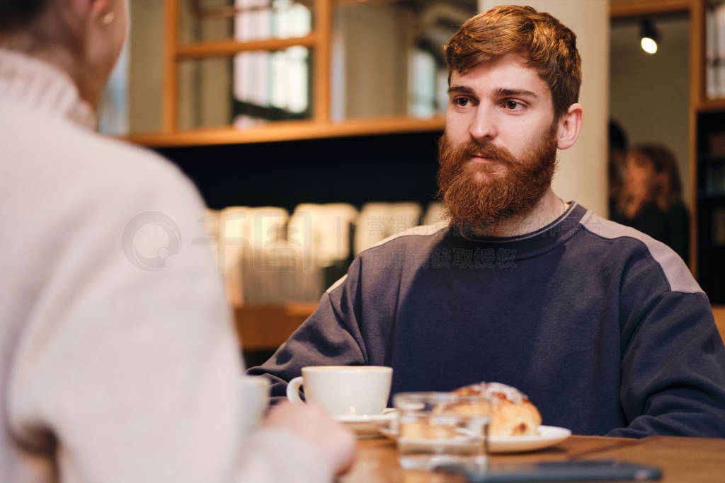 Young attractive bearded man intently looking at girlfriend duri