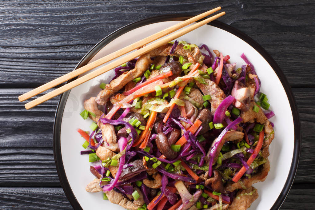 Tasty pork moo shu with cabbage mix and mushrooms close-up in a