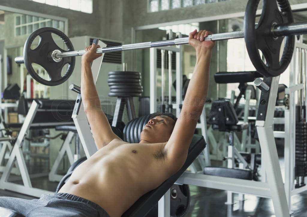 Young asian man lifting barbell in gym. healthy lifestyle