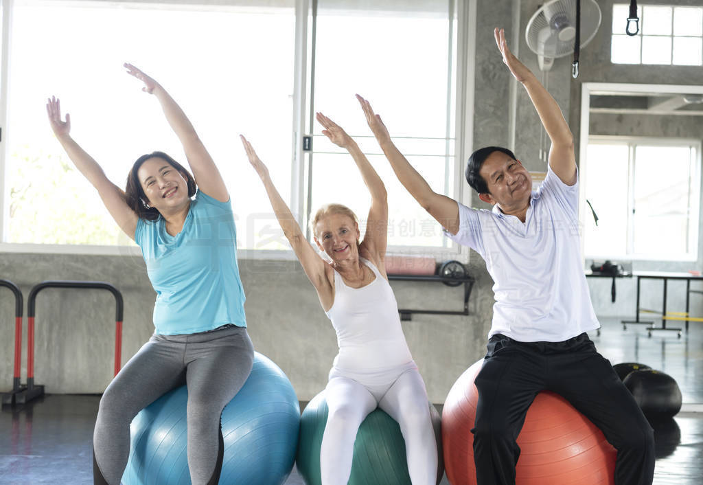 Group friend of senior at yoga gym sitting on her ball smiling