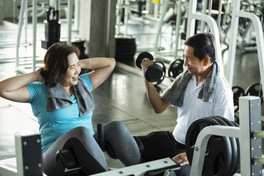 Asian senior man and woman exercise lifting dumbbell and sit up