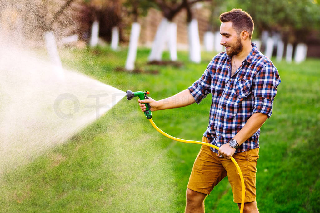 backyard gardening details - portrait of gardener using water ho