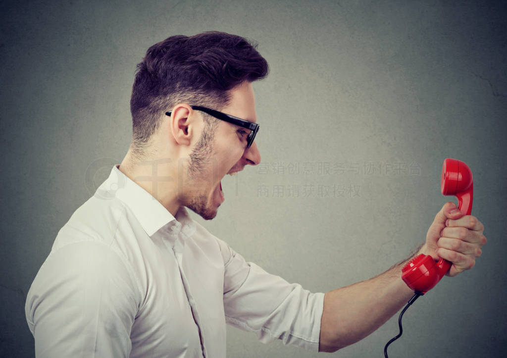 Angry businessman yelling on a red telephone